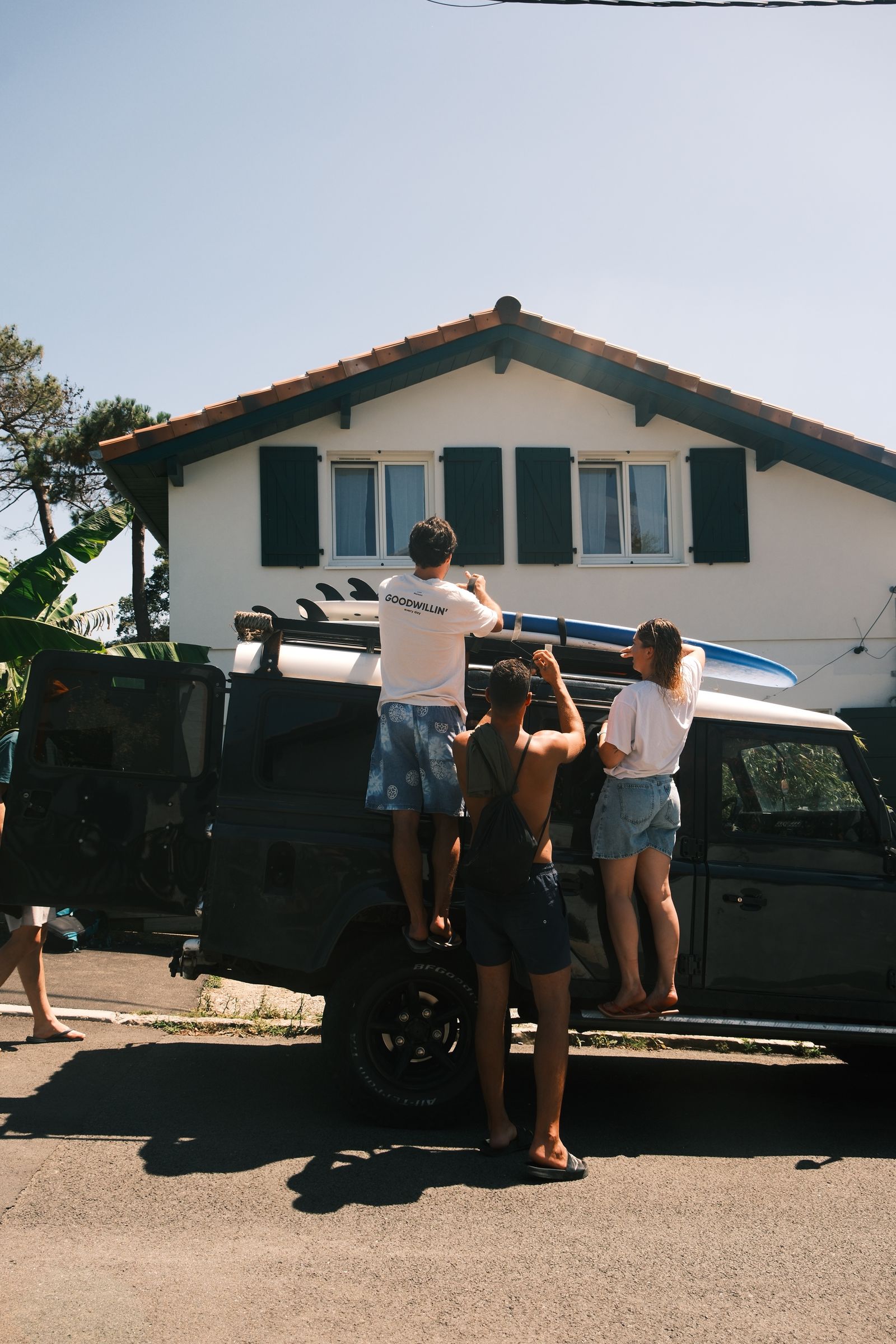 Friends strapping surfboards to the roof of a rental car