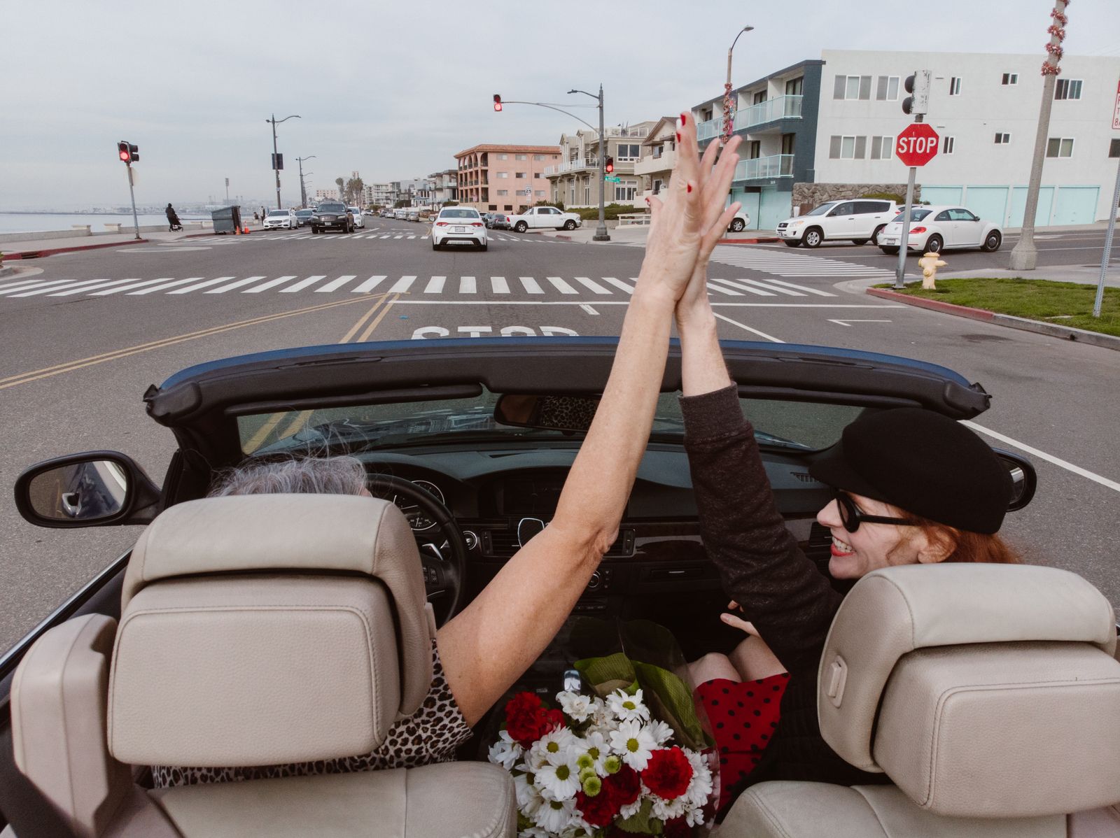 Two friends celebrating on a convertible drive along the coast